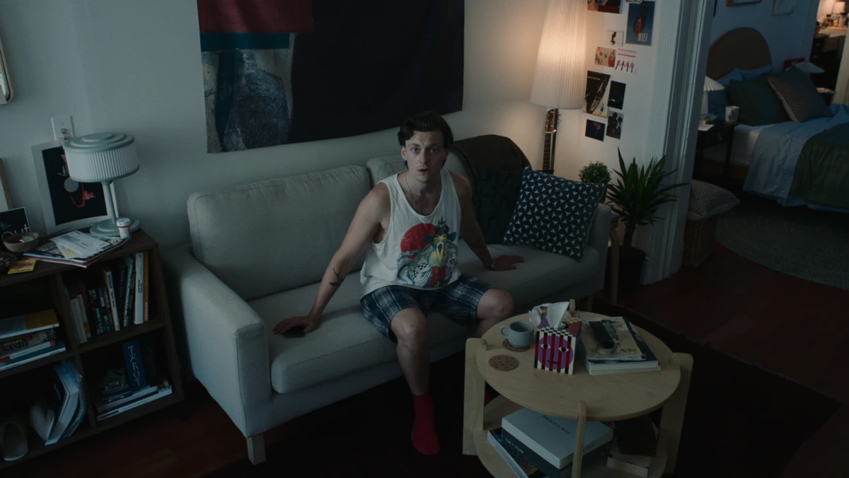 Jared on the living room couch, lamp on, snacks on the table.