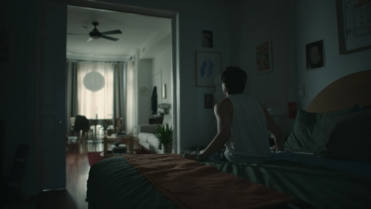 Jared on the edge of the bed, morning light through the blinds.
