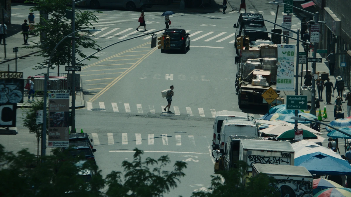 The intersection from above, traffic threading the crosswalk.