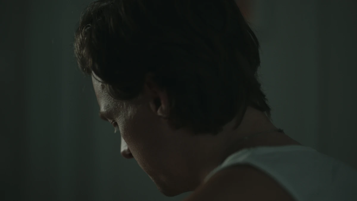 Jared in profile, white tank, lost in thought.