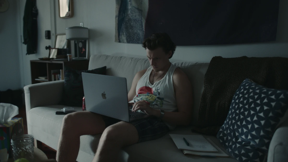 Jared with his laptop on the couch, notes on the cushion.